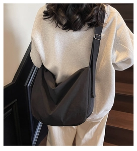Detail of a black minimalist large tote bag with a wide adjustable shoulder strap on a model