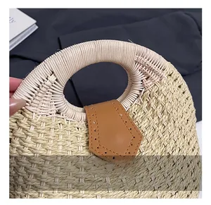 Close-up of woven straw handbag featuring a round handle and brown leather buckle