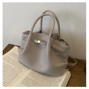 Detail view of grey pleated bucket bag with lychee grain leather on a book