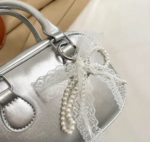Detail showing metallic silver leather texture with lace bow and pearl chain handle
