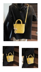 Details einer gelben Eimertasche mit Ledermuster, Perlenherz und Schleifenanhänger
