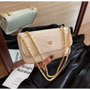 Close-up of beige quilted chain bag with gold metal logo and elegant V-shaped stitching