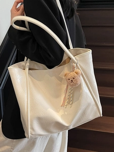 Creamy white oil wax leather tote bag with bear charm on model in dark staircase