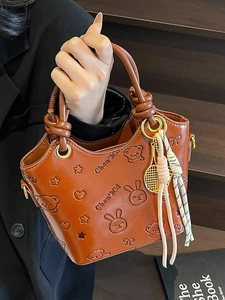 Caramel embossed PU leather bucket bag with cute charms and woven tassels for women