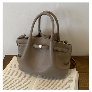 Detailed macro view of taupe leather bucket bag with golden buckle and sleek carry handles