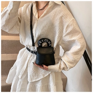 Detail of black mini crossbody bag featuring a circular handle with cat embroidery