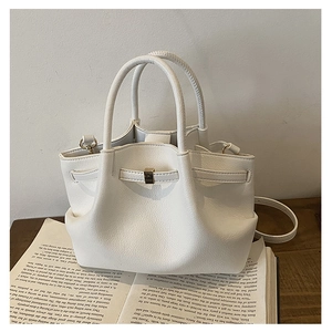 Detailed view of white bucket bag with pebble texture on book in a minimalist setting