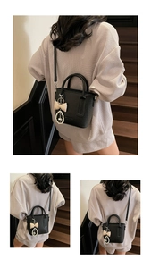 Detailansicht der schwarzen Lederhandtasche mit Perlenherz-Anhänger und Schleife