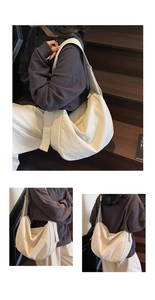 Detail view of a large cream canvas crossbody bag with wide adjustable strap and zipper
