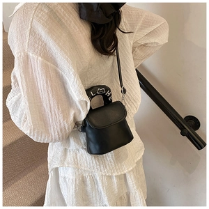 Detail of black semi-circular crossbody bag featuring cat embroidery on the handle
