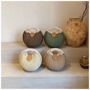 Detail of four different colored handmade circular straw handbags with leather accents