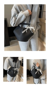 Close-up of black lychee grain leather bucket bag with lace pearl bow decoration