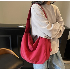 Macro shot of a red large capacity canvas messenger bag worn by a model in casual style