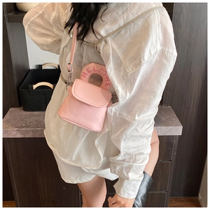 Detail view of pink mini handbag featuring Hello Kitty design on a unique metal handle