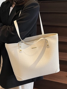 White woven large capacity tote bag with gold hardware shown on a model's shoulder