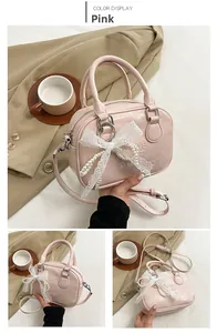 Détail du sac bowling en cuir rose avec lettres embossées, nœud en dentelle et perles