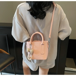 Detailansicht der rosa Leder-Eimertasche mit Perlen-Schleifenanhänger und Logo