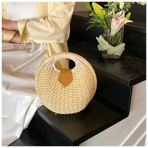 Detail of round straw handbag on wooden stairs with elegant flowers and soft lighting