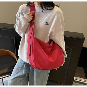 Close-up of a large red canvas hobo tote bag worn as a crossbody by a model