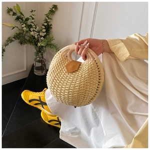 Detail of round straw handbag with circular top handles and brown leather buckle