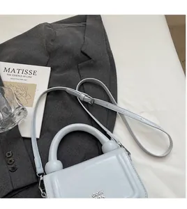 Détail du sac à main en cuir bleu clair avec poignée cylindrique et garnitures argentées
