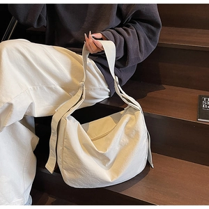 Large cream-colored casual tote bag with wide strap on a model sitting on wooden steps