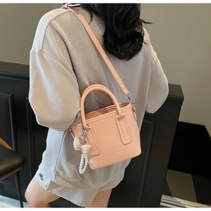Detail der rosa Bucket Bag mit Litschimuster, Perlen-Schleifen-Anhänger und Logo-Prägung