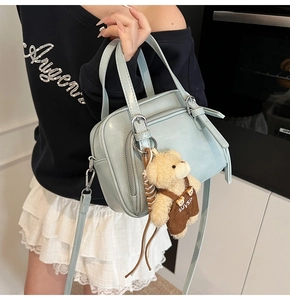 Detail of mint green oil wax leather crossbody bag with cute plush bear charm