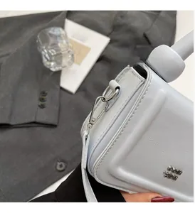 Détail du sac à main en cuir bleu clair montrant le logo argenté et les ferrures