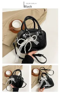 Détail du sac bowling en cuir verni noir avec nœud en dentelle et perles gaufrées