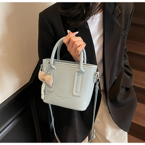 Detailansicht der hellblauen Lederhandtasche mit Litschi-Muster und Perlenanhänger