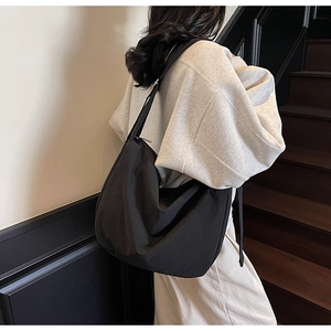 Side view of large black slouchy hobo tote bag with wide adjustable shoulder strap