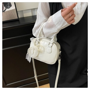 Vue détaillée du sac bowling blanc orné d'un nœud en dentelle et perles
