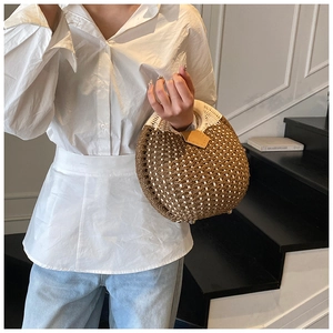 Detail of hand-woven straw bag with two-tone pattern and sturdy metal base feet