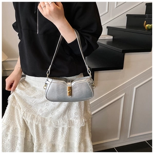 Sac bandoulière argenté avec fermoir doré porté par un mannequin dans un style épuré