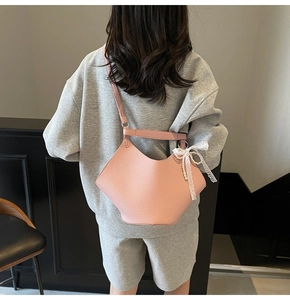 Detailed back view of pink lychee textured crossbody bag with lace bow and pearl charm