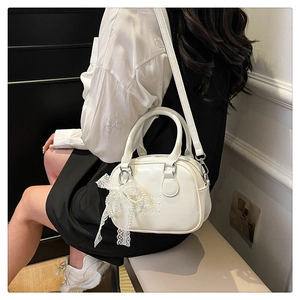 Détail du sac bowling en cuir blanc avec nœud en dentelle perle et motif gaufré