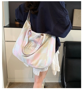 Rear view of a model carrying a large plaid tote bag with Meal text and long shoulder straps