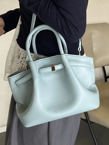 Light blue pleated leather bucket bag with top handles and golden buckle detail