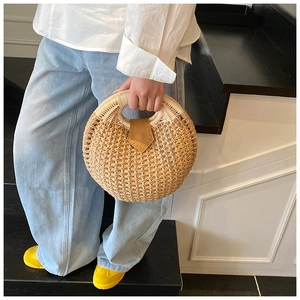 Detailed view of a round straw handbag with leather clasp and woven circular handle