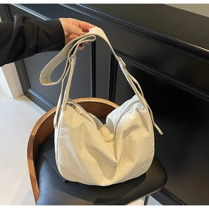 Detail view of white waterproof nylon crescent tote bag with wide adjustable shoulder strap