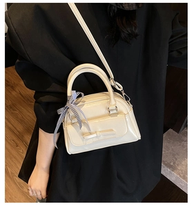 Détail du sac en cuir verni blanc cassé avec nœud et poignée ruban à carreaux