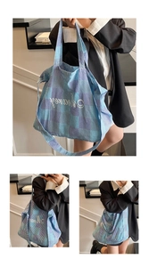 Detail of blue and purple plaid tote bag featuring white cursive embroidery and wide strap