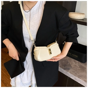 Détail d'un sac bandoulière crème avec fermoir rotatif doré et fine bandoulière