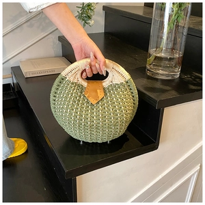 Detail of green straw woven round bag with brown leather buckle and cream top handle