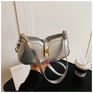 Détail du sac sous le bras argenté avec fermoir doré et design incurvé élégant