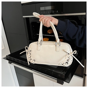 Dettaglio della borsa sottobraccio in pelle PU bianco crema con fiocchi laterali decorativi