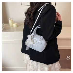 Détail du sac bowling bleu clair avec nœud en dentelle perlée et bandoulière réglable