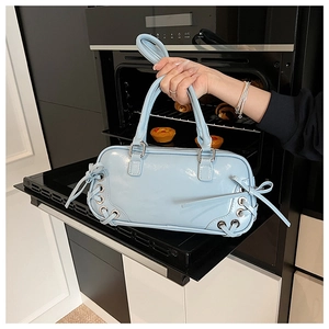 Dettaglio borsa in pelle lucida azzurra con fiocchi e occhielli in metallo argentato