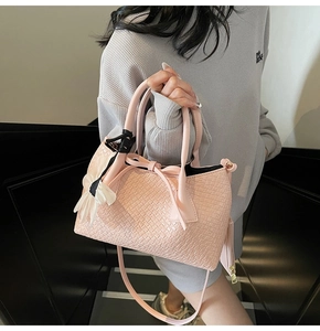 Pink woven texture tote bag with bow detail and matching mini charm pouch in hand